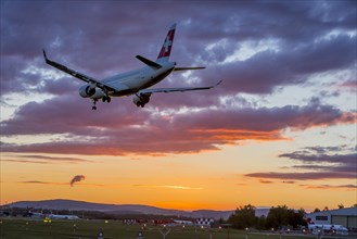 ZRH Airport with aircraft on approach of the airline Swiss, Bombardier BD-500, sunset, Zurich, Switzerland, Europe