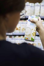 Younger woman buys soya milk at the supermarket. Radevormwald, Germany, Europe