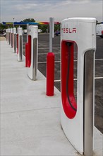 Elkhart, Indiana, Charging stations for Tesla electric vehicles next to a Sunoco gas station on the Indiana Toll Road