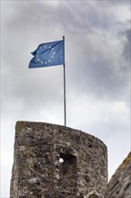 European flag on the 13th century town fortifications, with town wall, battlements and witchs tower, Hillesheim, Rhineland-Palatinate, Germany, Europe