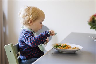 Bonn. Toddler eats a meal of peas, carrots and cereals. Bonn, Germany, Europe