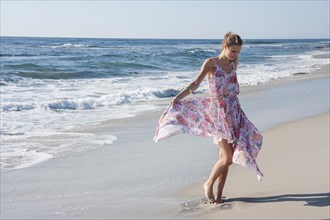 Beautiful young woman wearing a floral dress at the beach, La Jolla, California