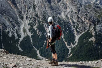 Tourist crossing the via ferrata trail with equipment in the dolomites. Dolomites