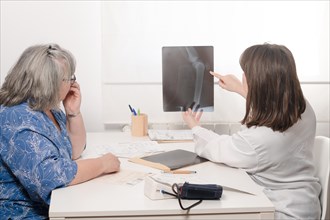Young woman doctor showing her elderly patient an x-ray