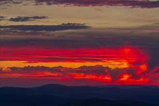 Clouds and sky lit by the colourful sun light of the sunset. The brilliant orange-red light of the sun reflects against the beautiful could formation in the warm sky. Aargau
