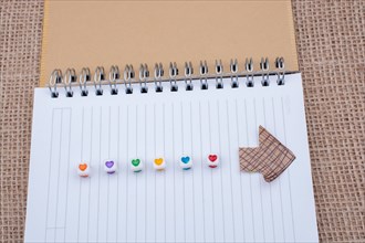 Love cubes and paper arrow on a notebook on canvas