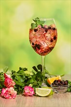 Cold sangria with dry rosebuds in wine glass with ingredients on a table over summer background