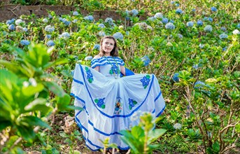 Portrait of young Nicaraguan woman in traditional folk costume in a field of flowers
