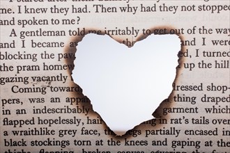 Heart shaped burnt out of a texted paper