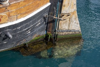 Detail of the stern and rudder of an old wooden ship in the sea