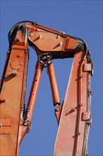 Orange hydraulic excavator arm of an excavator on a construction site