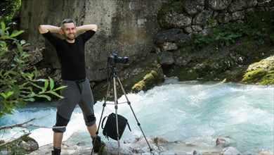 Smiling tourist takes a picture while standing in a river in the Dolomites. Dolomites