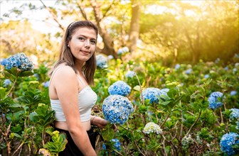 Woman in a hydrangea field. Beautiful girl in a natural flower nursery. Portrait of young woman in a hydrangea field. El Crucero