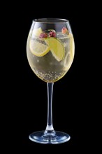 Cold white sangria with dry rosebuds in wine glass isolated on black background