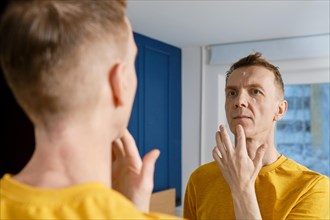 Middle-aged man applying anti-wrinkle cream. Male ageing problem
