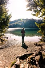 Hiking woman standing at the stand of Alatsee at sunrise
