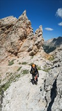 Tourist with equipment on a mountain trail in the Alps. Dolomites