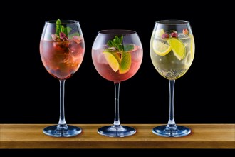 Set of wine glasses with cold sangria on wooden counter isolated on black background