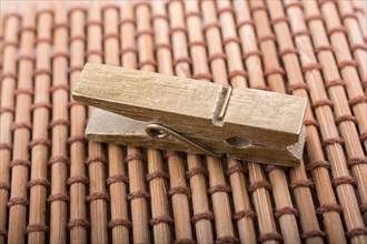 Small wooden clothespin placed on straw background