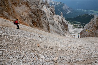 The descent of the tourist on the loose stones from the Forcella Staunies pass in the Dolomites. Dolomites