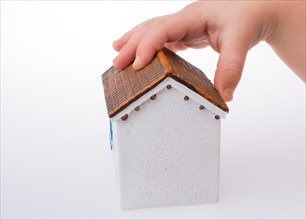 Little model house and a hand on a light white color background