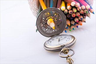 Retro style classic pocket watch and color pencils on white background
