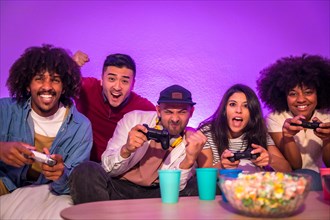 Adult party. Attractive young men sitting on the sofa playing video games with popcorn. With the joystick or controller in hand and look at the monitor