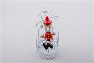 Metal cage and Little puppet pinocchio made of wood