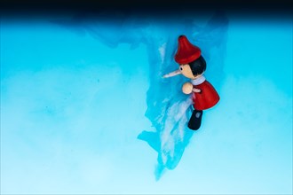 Wodden puppet Pinocchio on in blue water