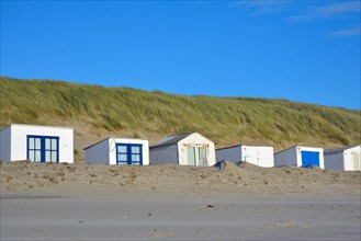 Row of white and blue beach sheds on the beach of island Texel in the Netherlands