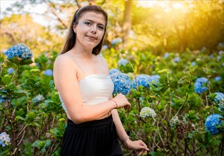 Portrait of young woman in a hydrangea field. Woman in a hydrangea garden
