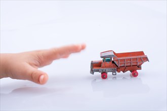 Baby hand is about to grab a red toy truck on white background