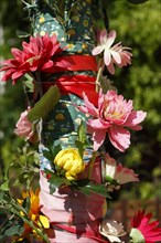 Pole of a streetlamp decorated with colourful artificial flowers