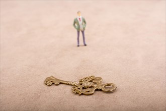 Figurine standing by a retro styled golden color key on a brown background
