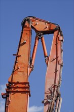 Orange hydraulic excavator arm of an excavator on a construction site