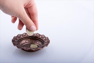 Hand giving away money to a metal bowl