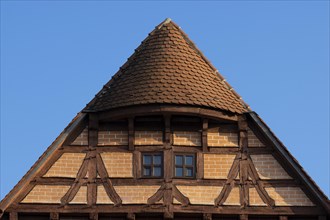 The orange top of the front part of the half-timbered house with the blue sky in the background