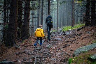 Mum and her little son go on a mountain trail in wet autumn weather. Polish mountains