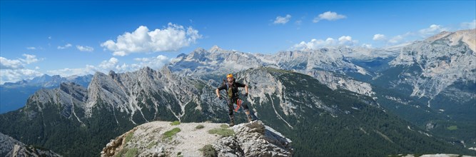 A tourist stands and poses against the backdrop of a mountain panorama in the Dolomites. Dolomites
