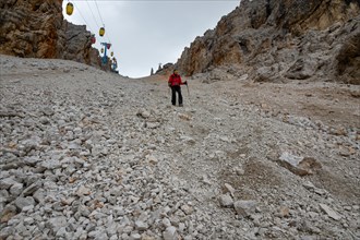 The descent of the tourist on the loose stones from the Forcella Staunies pass in the Dolomites. Dolomites