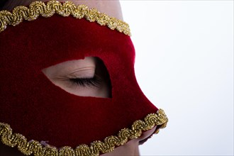 Child looks through carnival mask on liwhite background
