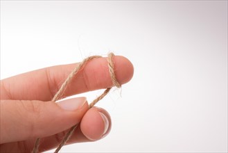 Hand holding linen thread on a white background