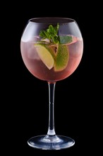 Cold sangria with lime and mint in a wine glass isolated on black background