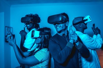 Group of young people in vr glasses in a virtual reality game in a blue light with guns