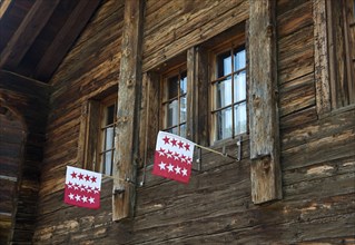 Two flags of the Canton of Valais in the window of a Swiss chalet