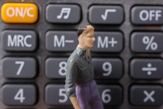 Tiny figurine of man model on a calculator