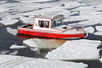 Small red boat between ice sheets