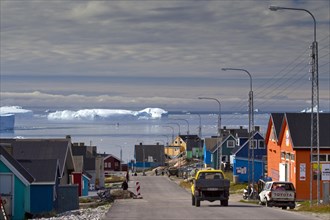 Iceberg and colourful houses in the town Ilulissat