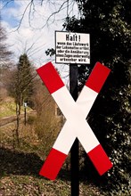 Warning sign for pedestrians in the forest along a railway line