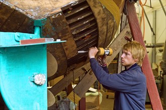 Boat builder restoring the hull of a wooden boat at the Winkler shipyard in Bremen Lesum